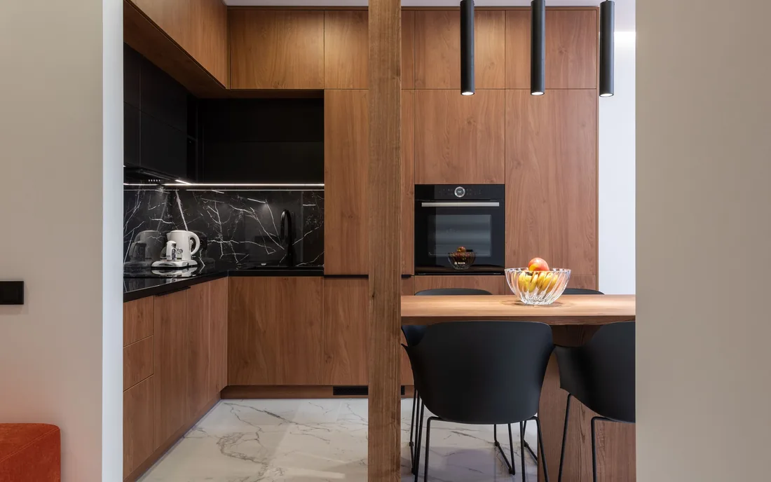Bucătărie în L cu fronturi decor nuc, corpuri negre și placare imitație marmură